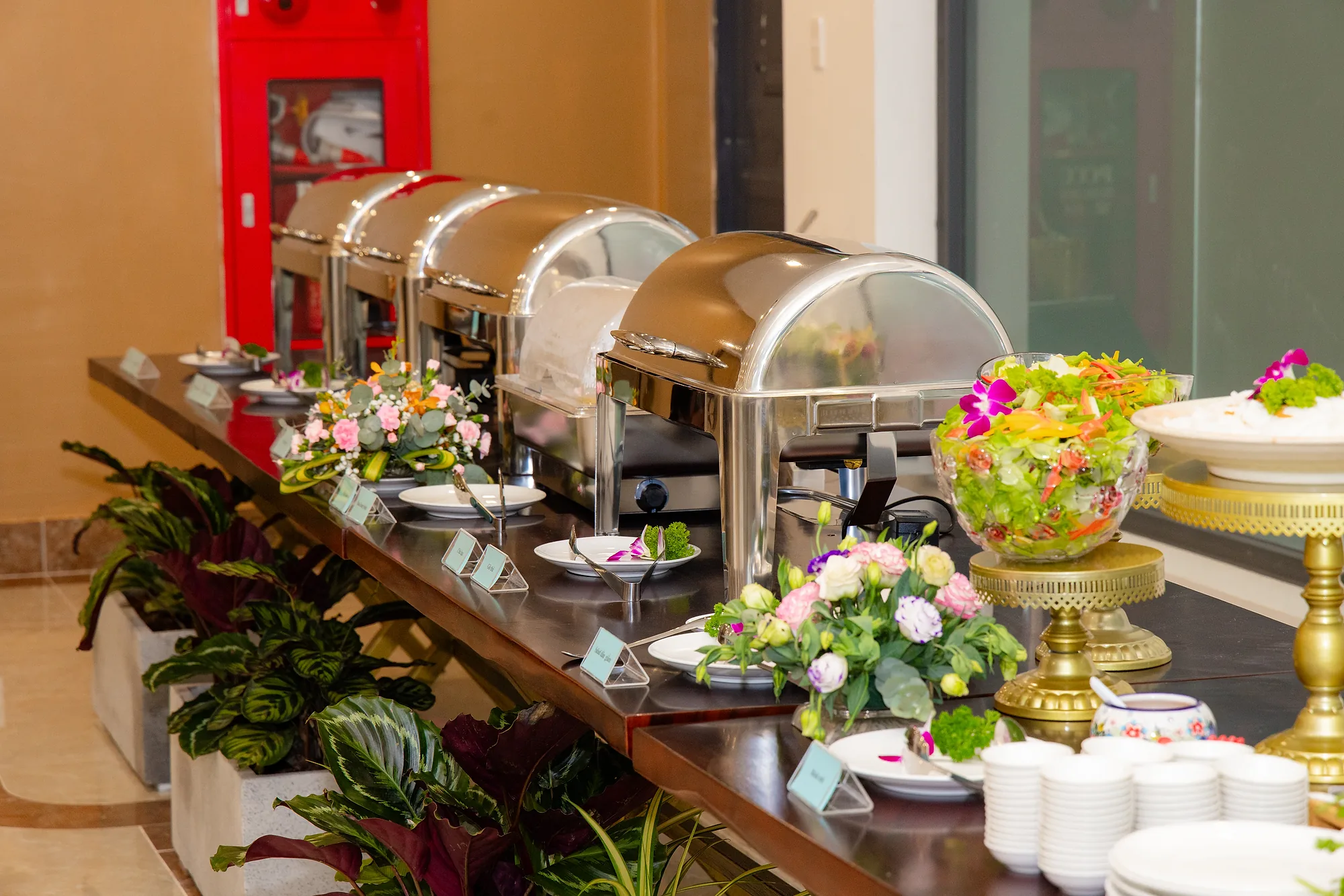 Quầy buffet với khay hâm nóng và hoa tươi
